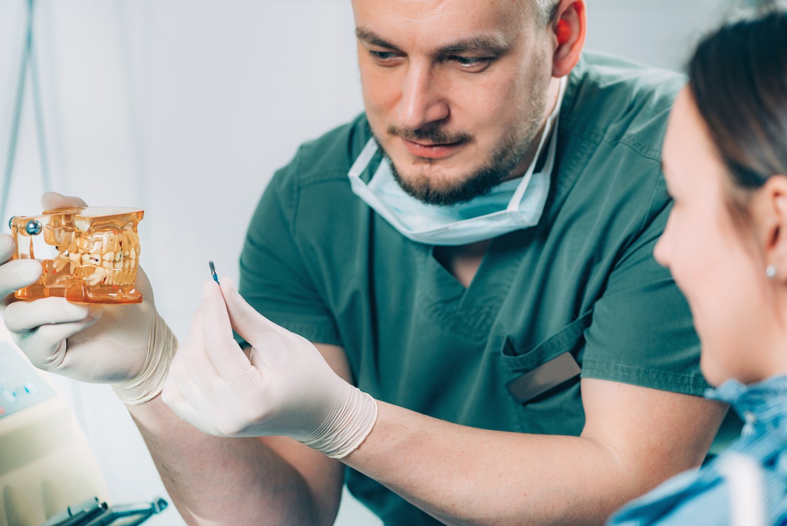 Dentista explicando un tratamiento con un modelo dental a una paciente