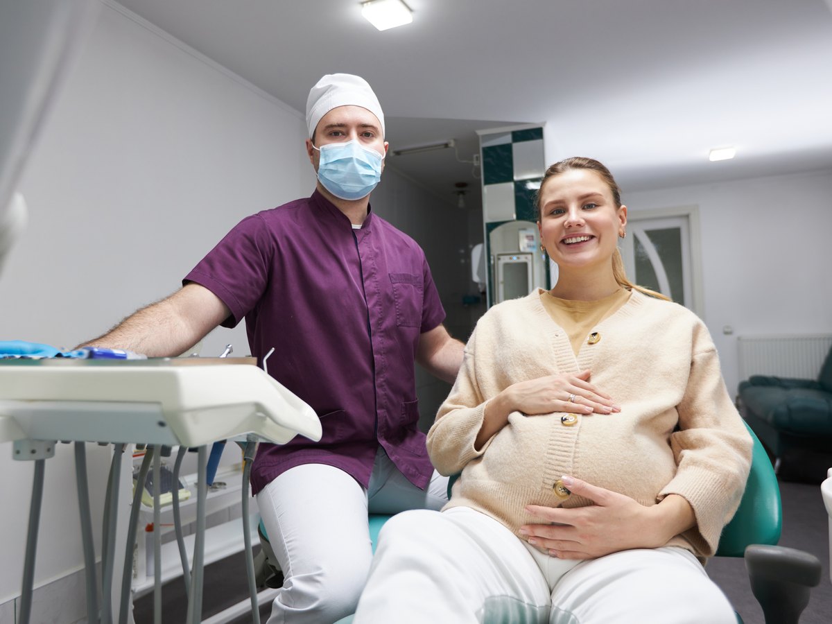 Mujer embarazada sentada en el sillón dental junto a su dentista