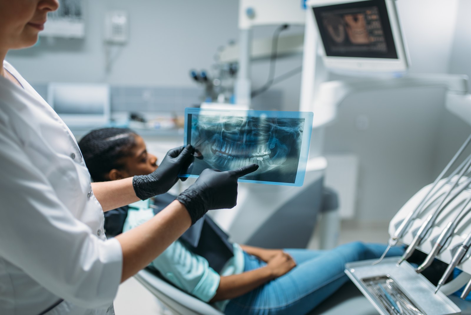 Dentista mostrando una radiografía panorámica a una paciente en el sillón dental
