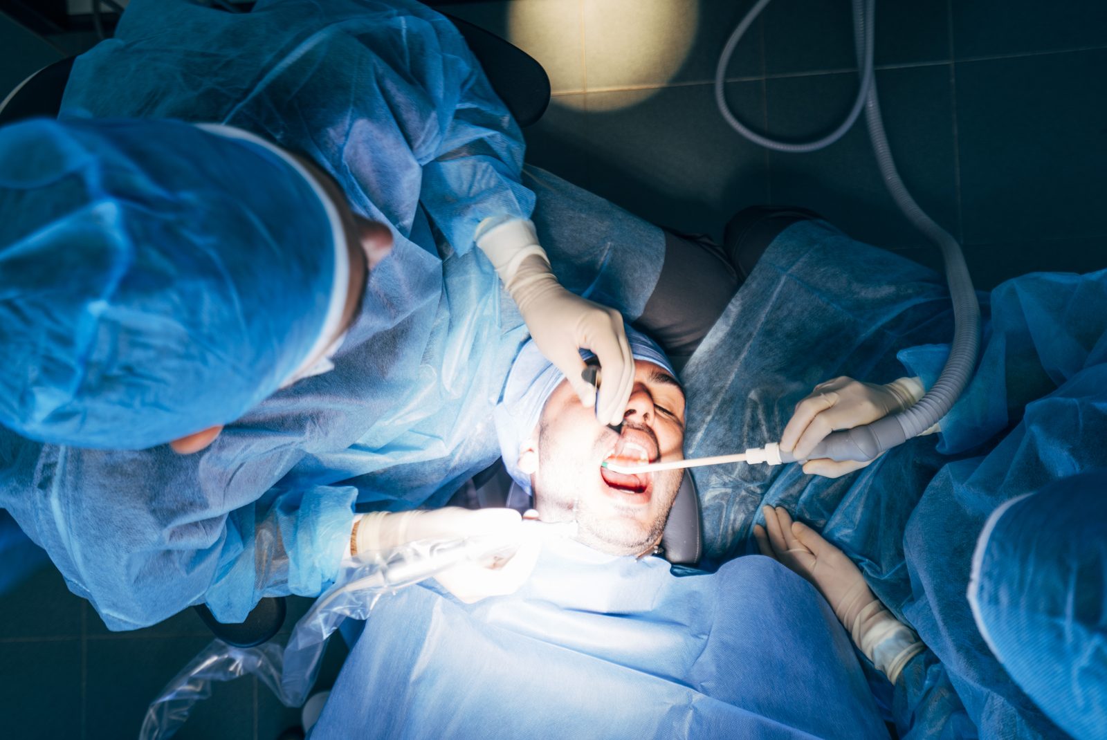 Equipo de cirujanos dentales atendiendo a un paciente en quirófano
