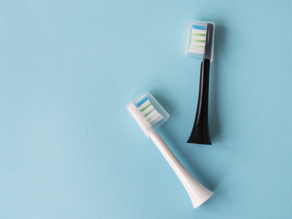 Dos cabezales de recambio de cepillo de dientes eléctrico con su capuchón sobre fondo azul