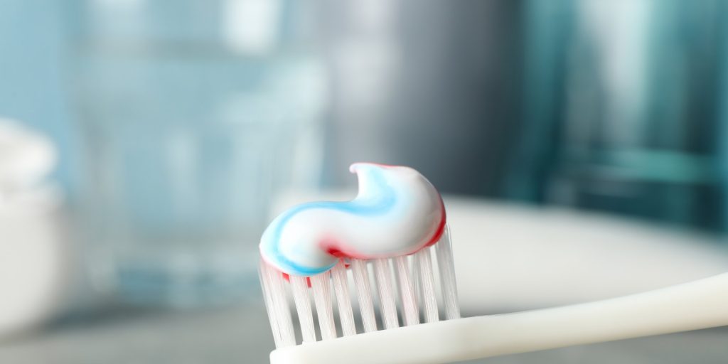 Cepillo de dientes con pasta dental de rayas sobre el lavabo del baño