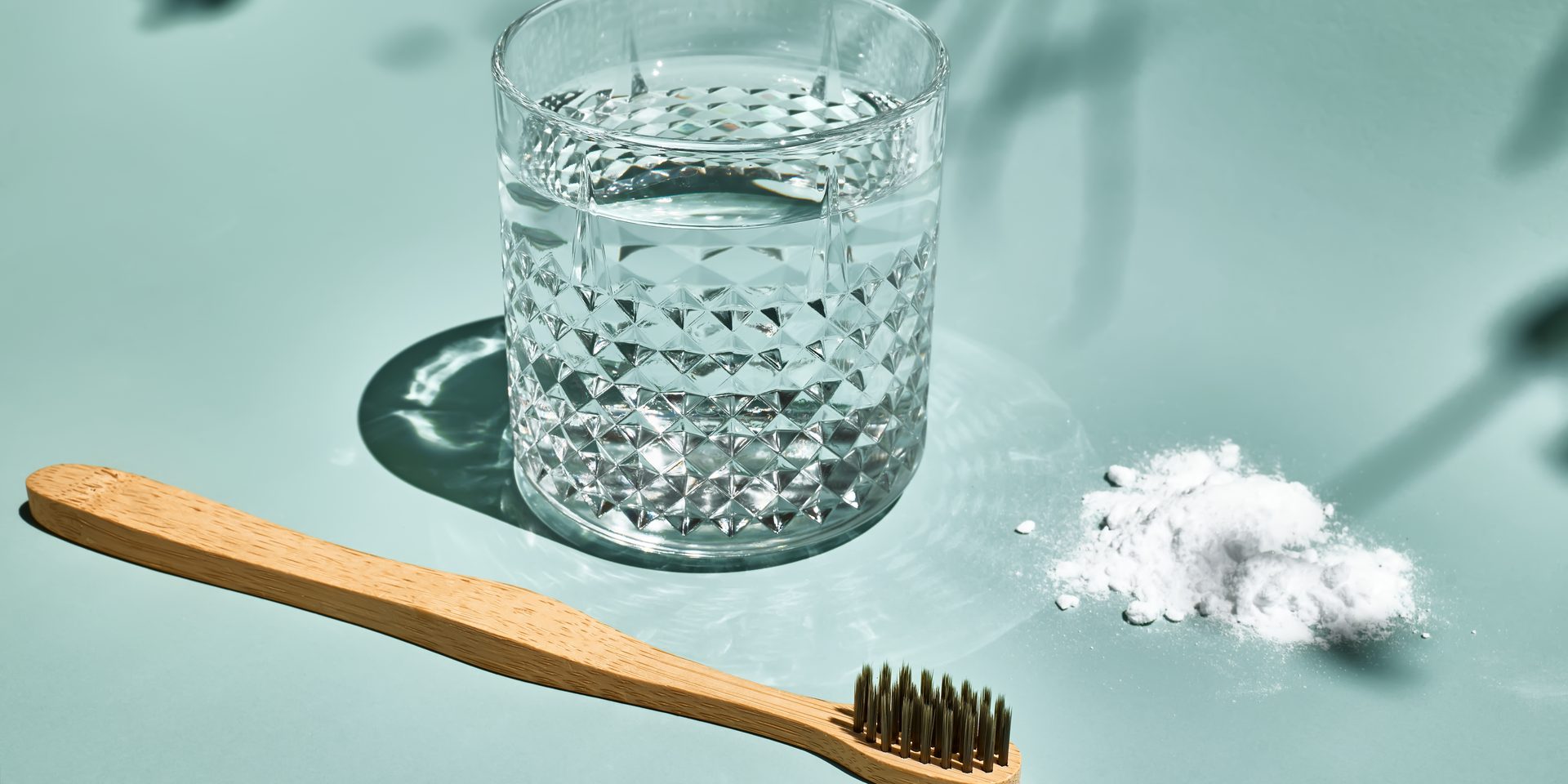 Cepillo de dientes manual de bambú junto a un vaso de agua