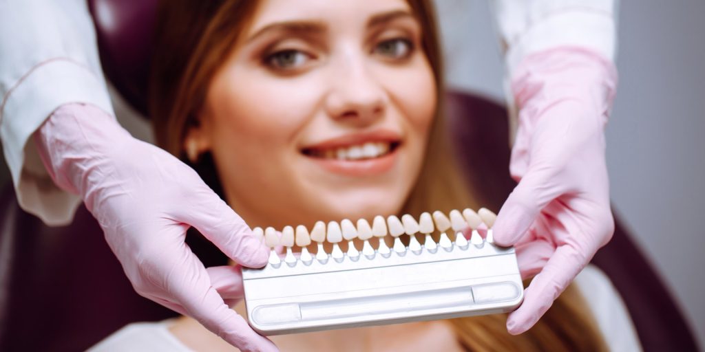 Paciente sonriente con la guía de colores dentales delante de la boca