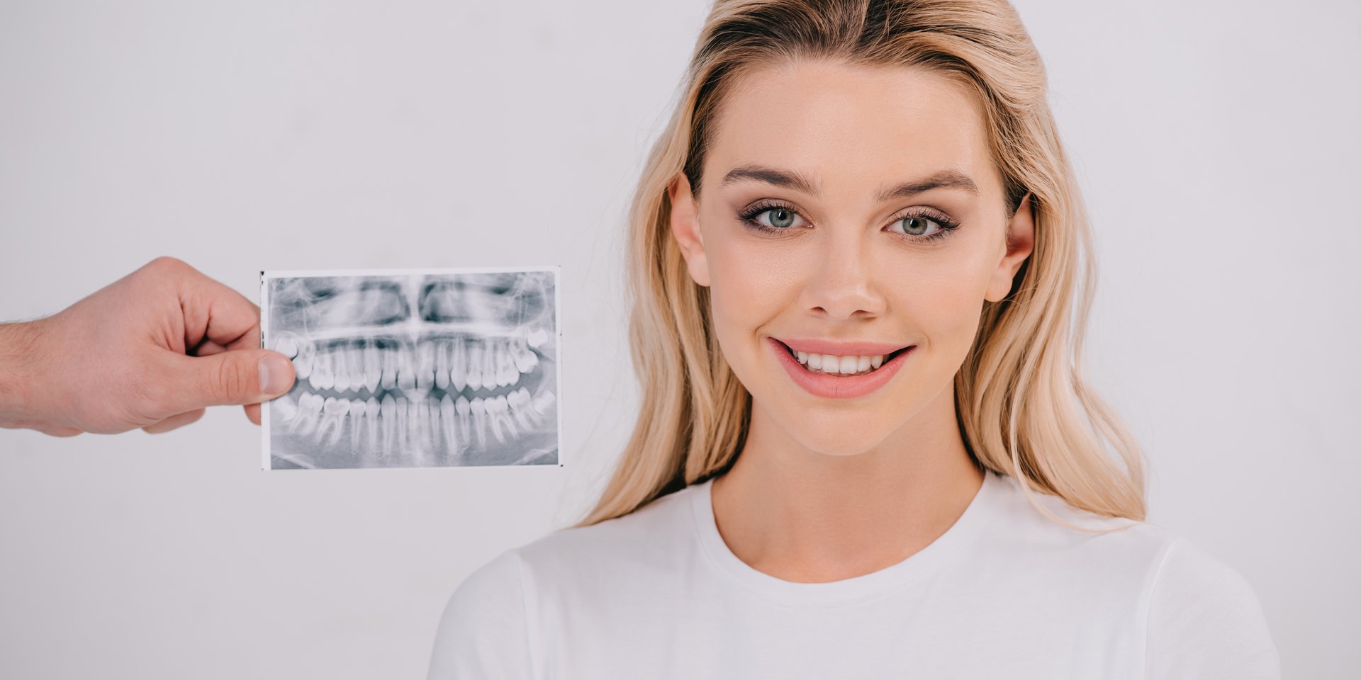 Radiografía panorámica de los dientes junto a una paciente sonriente