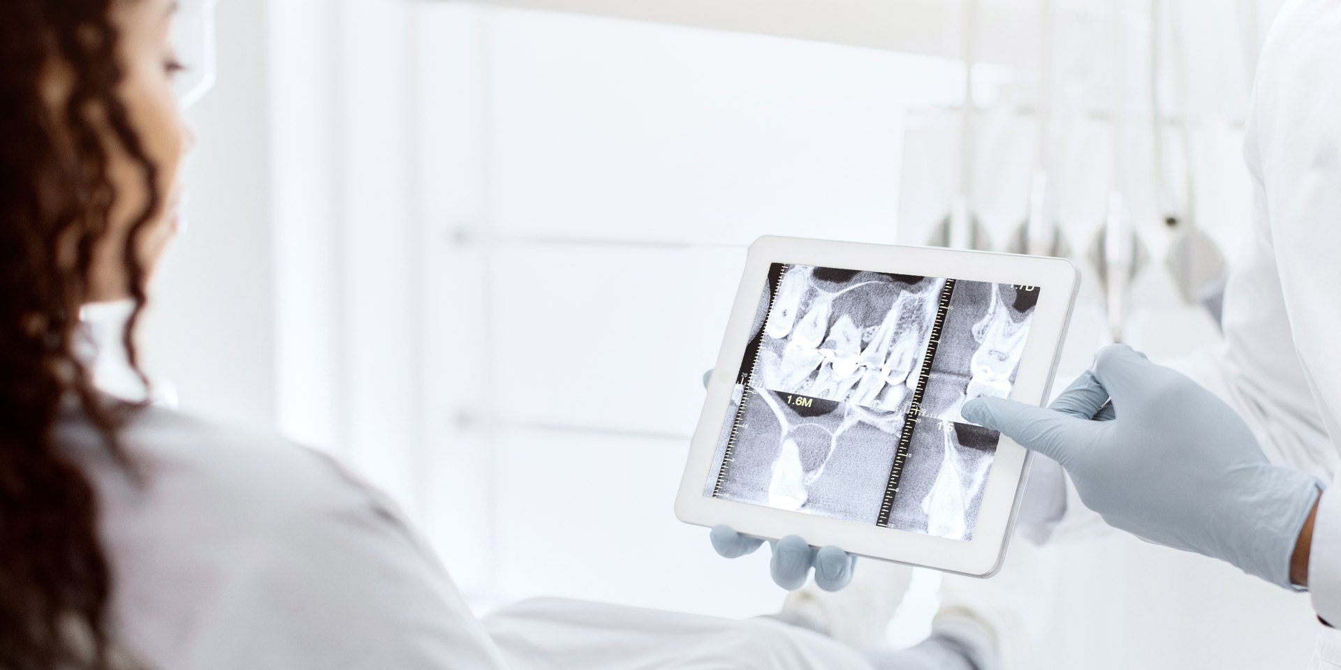 El dentista enseña a una paciente su radiografía dental en una tableta