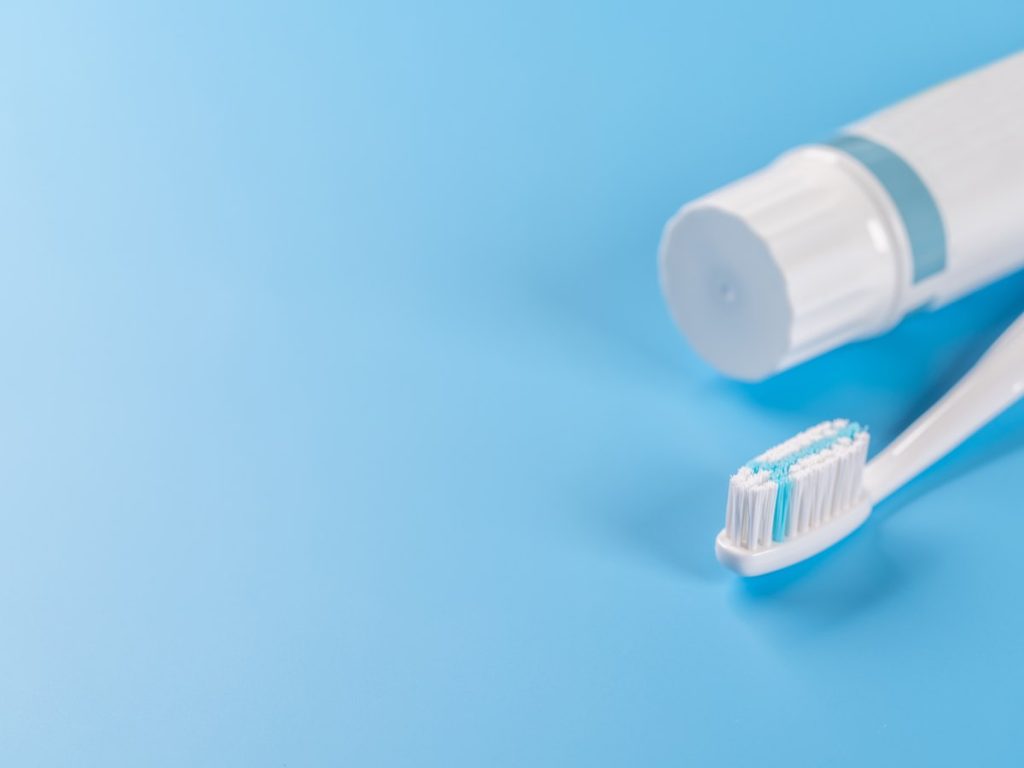 Tubo de pasta de dientes y cepillo sobre fondo azul