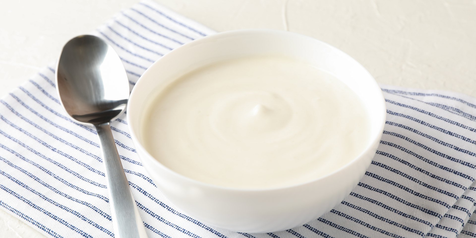 Cuenco de yogur con una cuchara, comida blanda para los días después de una extracción